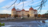 Barockschloss mit vier runden Ecktürmen an einem Seeufer im Herbst.