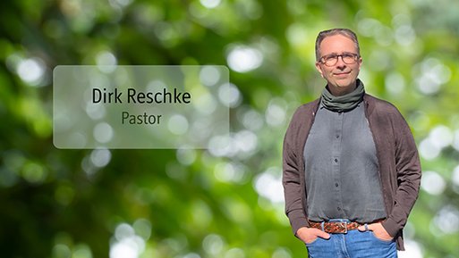 Dirk Reschke Dirk Reschke Mann mit Brille, grauem Pullover und brauner Jacke steht vor unscharf grünem Hintergrund mit Text 'Dirk Reschke Pastor'.